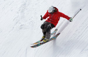 مردی در حال اسکی کردن روی کوه پوشیده از برف است
